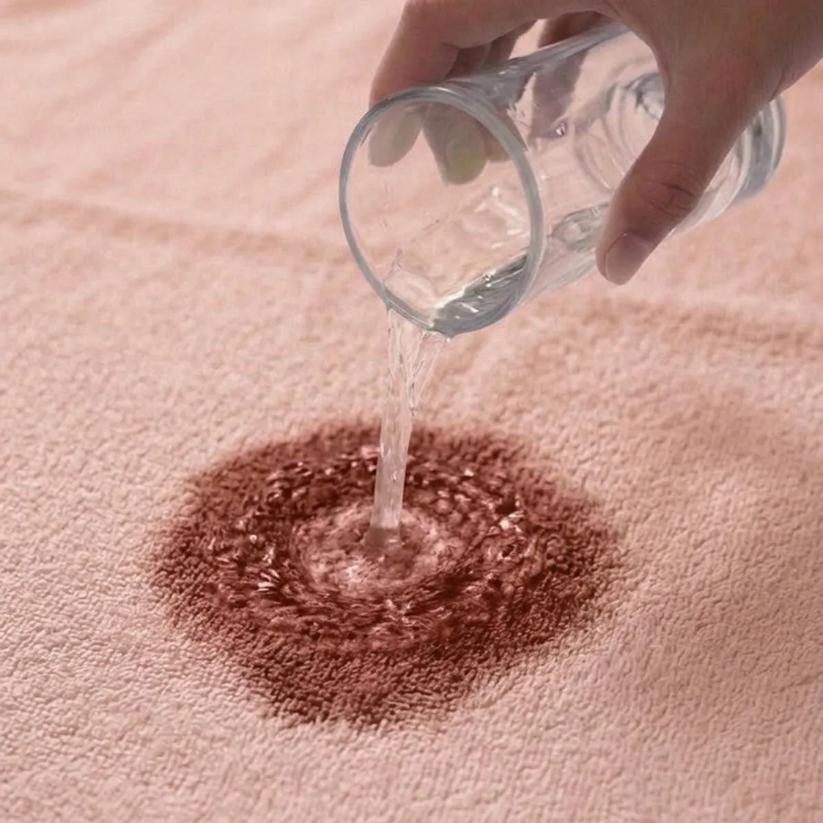 Water being poured onto the absorbent surface of a pink bath towel