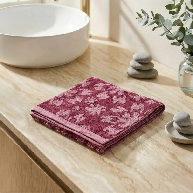 Folded maroon floral bath towel displayed on a bathroom counter.