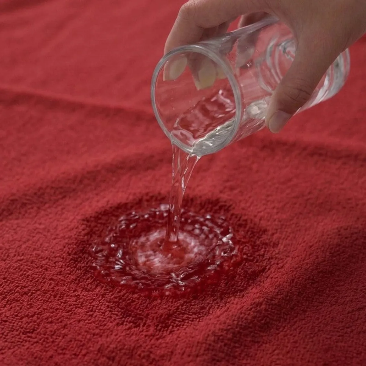 Water being poured onto the absorbent surface of a red towel