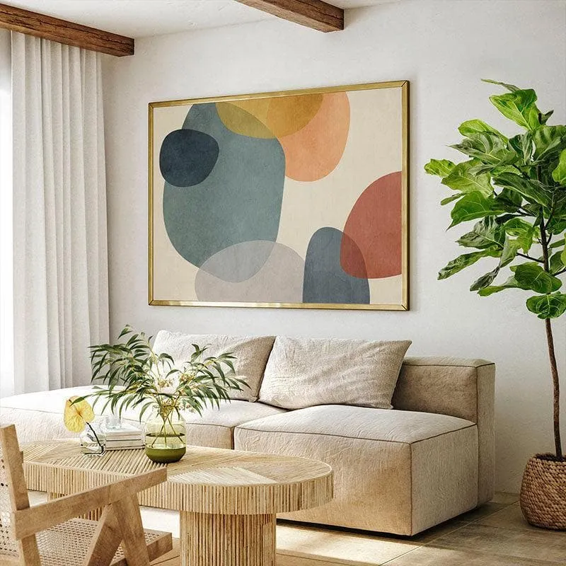 Abstract geometric wall painting in a gold frame above a beige sofa in a warm living room