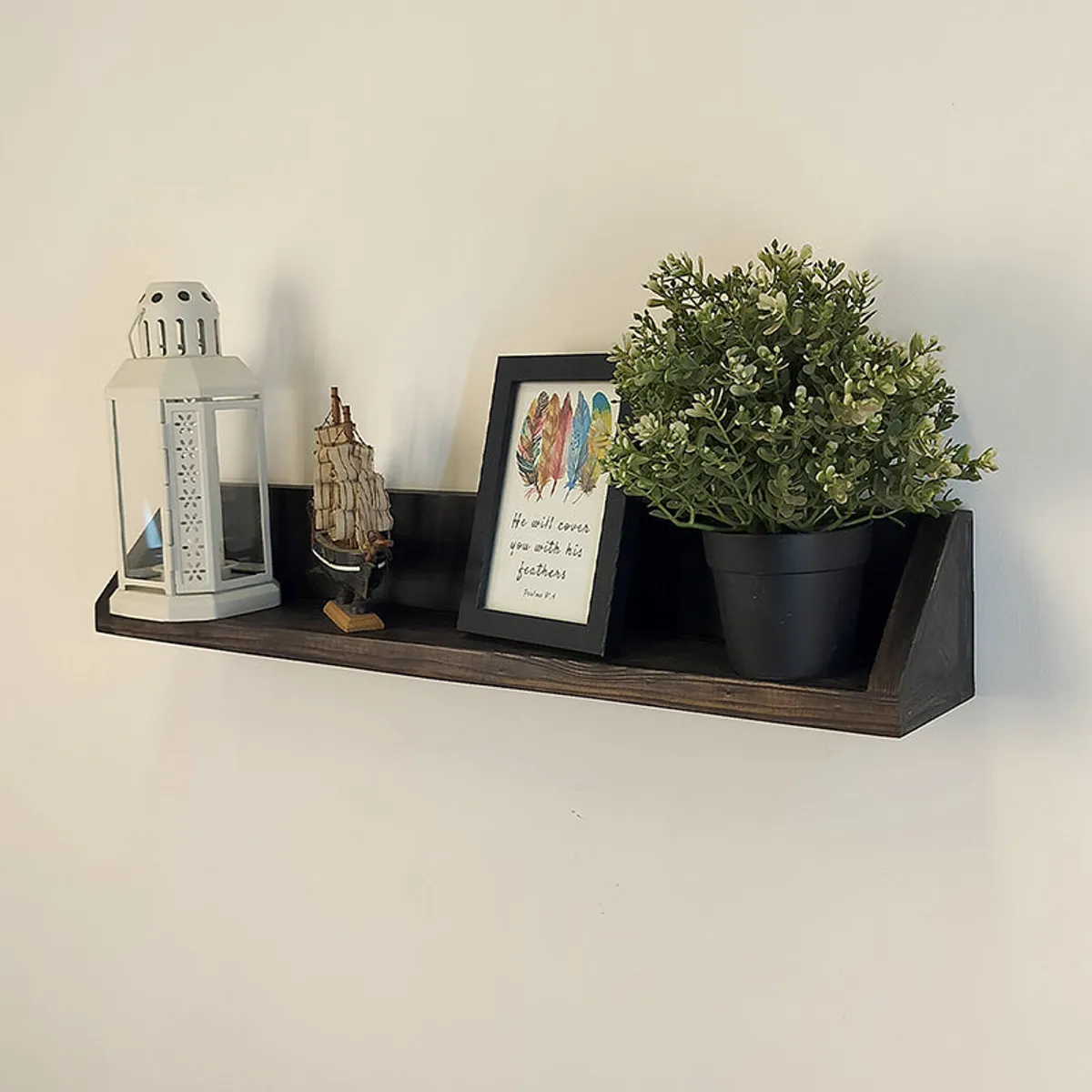 Angled view of a brown wooden wall shelf with decorative objects and a potted plant.