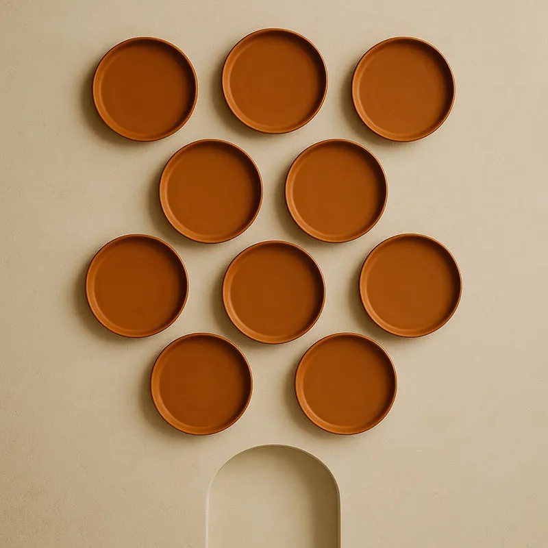 Ten round brown wall plates arranged in a symmetrical display above an arched alcove