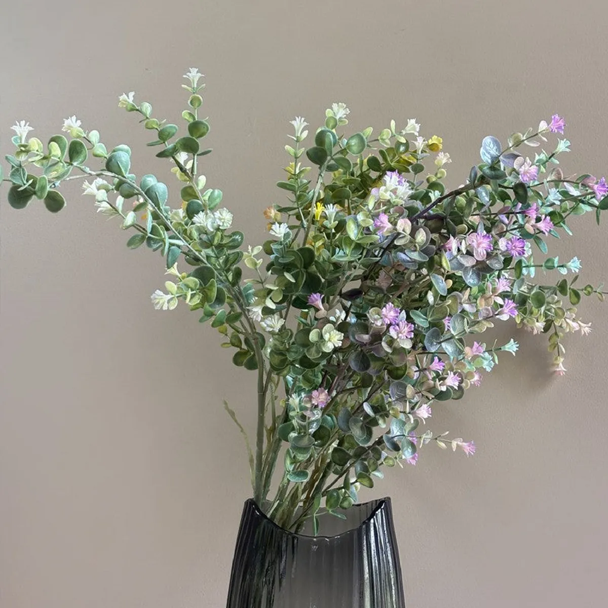 Close view of the flowering artificial eucalyptus branch with green foliage and pastel blooms