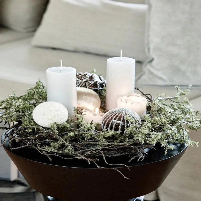 White pillar candles styled in a decorative bowl with natural accents