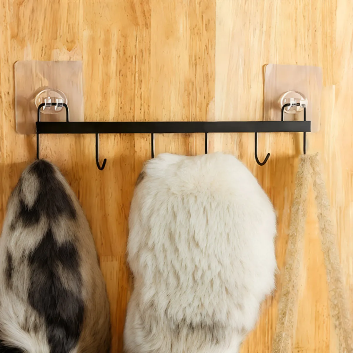 Black wall hook rack mounted on a warm wooden wall and holding hanging items.