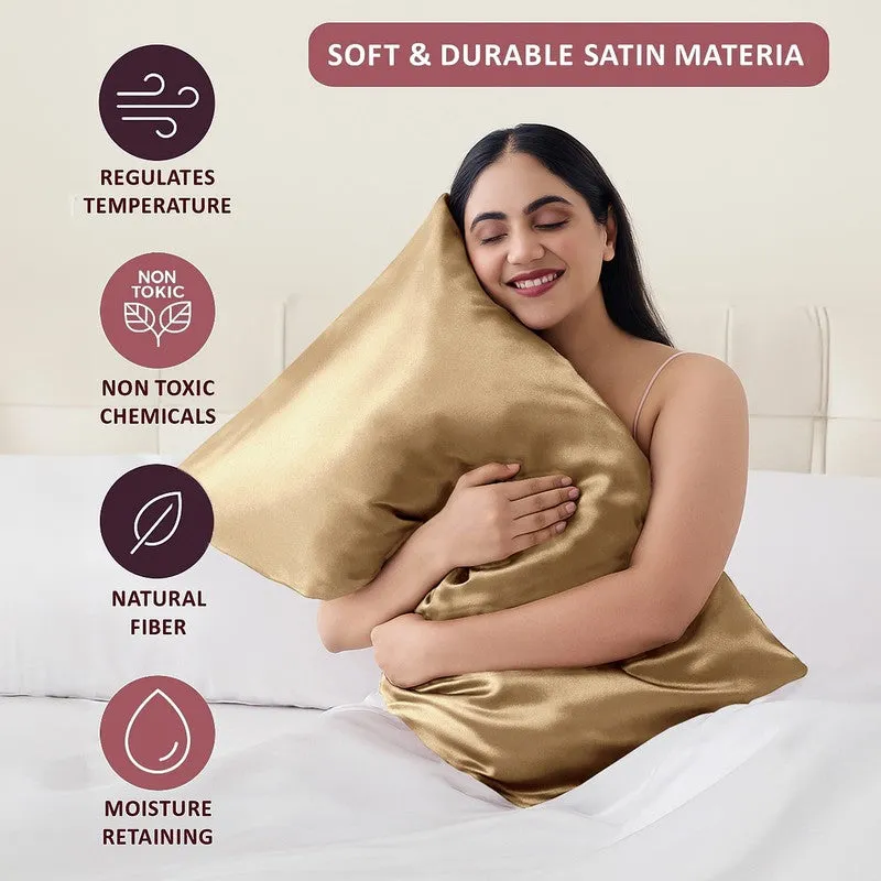 Person holding a gold satin pillow cover in a bedroom.