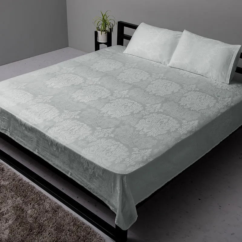 Light grey floral fitted bedsheet styled on a bed with matching pillows