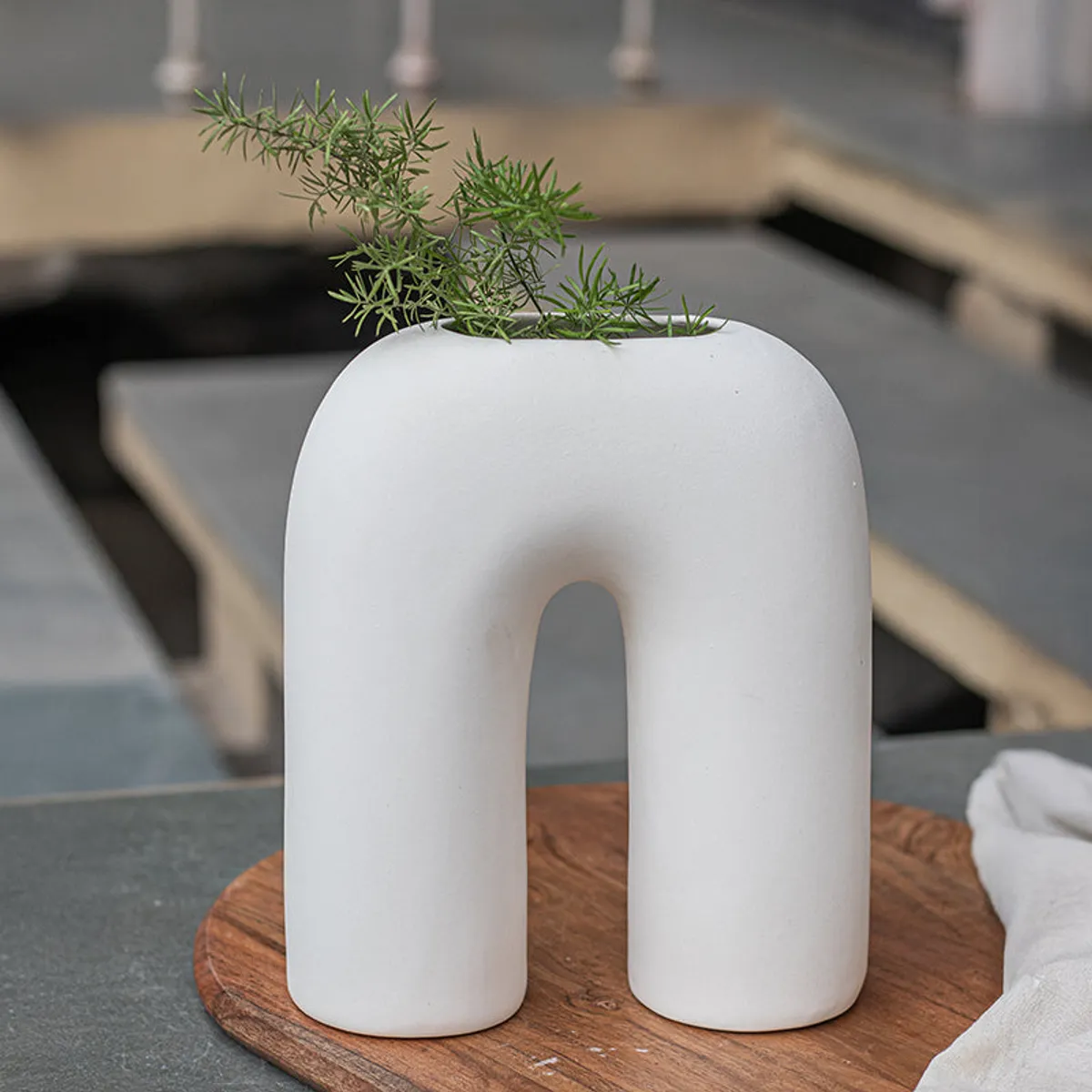 Front view of a white arc-shaped ceramic vase with foliage