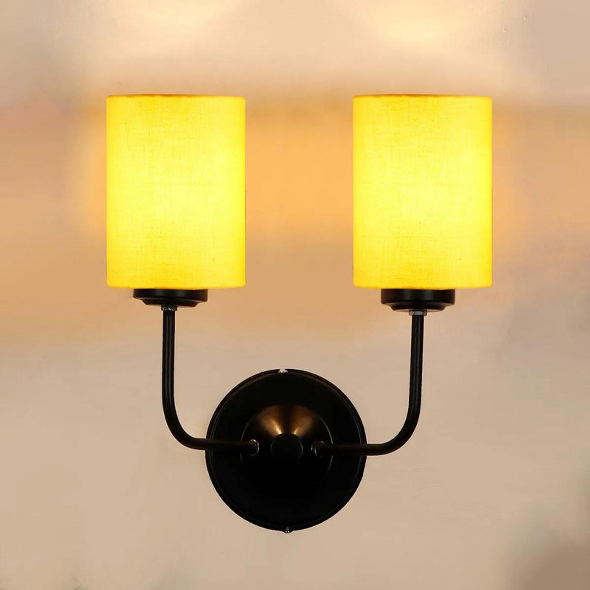 Front view of yellow twin-shade wall lamp with black iron base