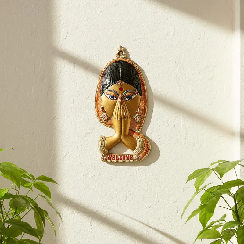 Namaste-style wall accent with folded hands in peach and gold on a wall