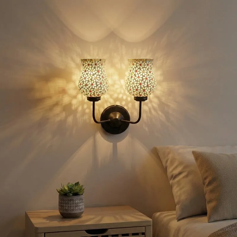 Twin ivory mosaic glass wall lamp lit on a wall above a bedside table