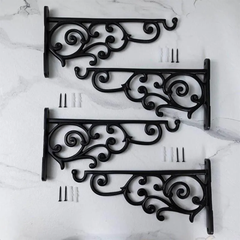 Four black ornate wall brackets displayed with mounting screws on a light surface.