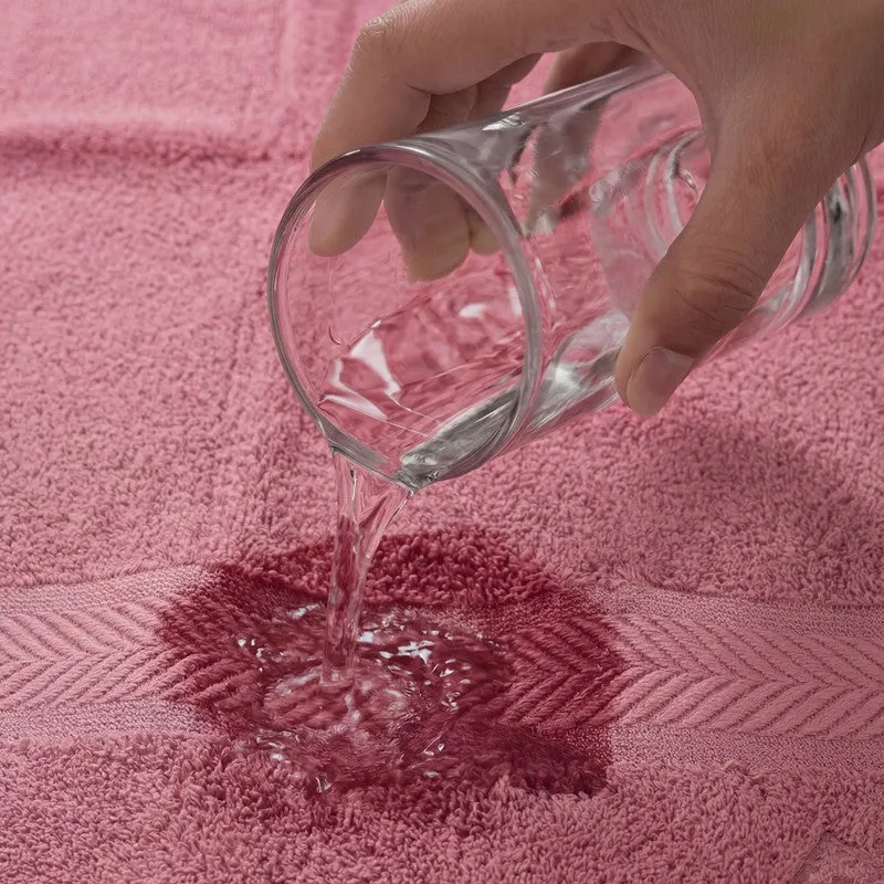 Water being poured onto a pink bath towel