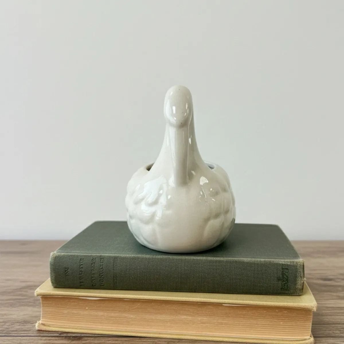 White swan vase with a curved neck on a wooden surface
