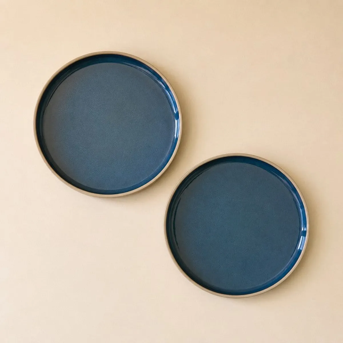Two blue round quarter plates shown from above on a beige surface