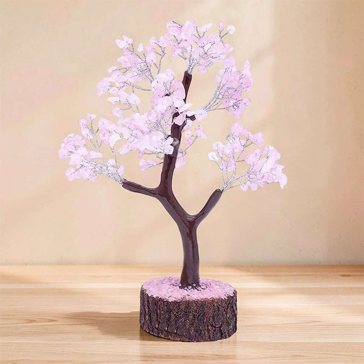 Pink crystal wish tree showpiece on a wooden tabletop against a warm beige wall