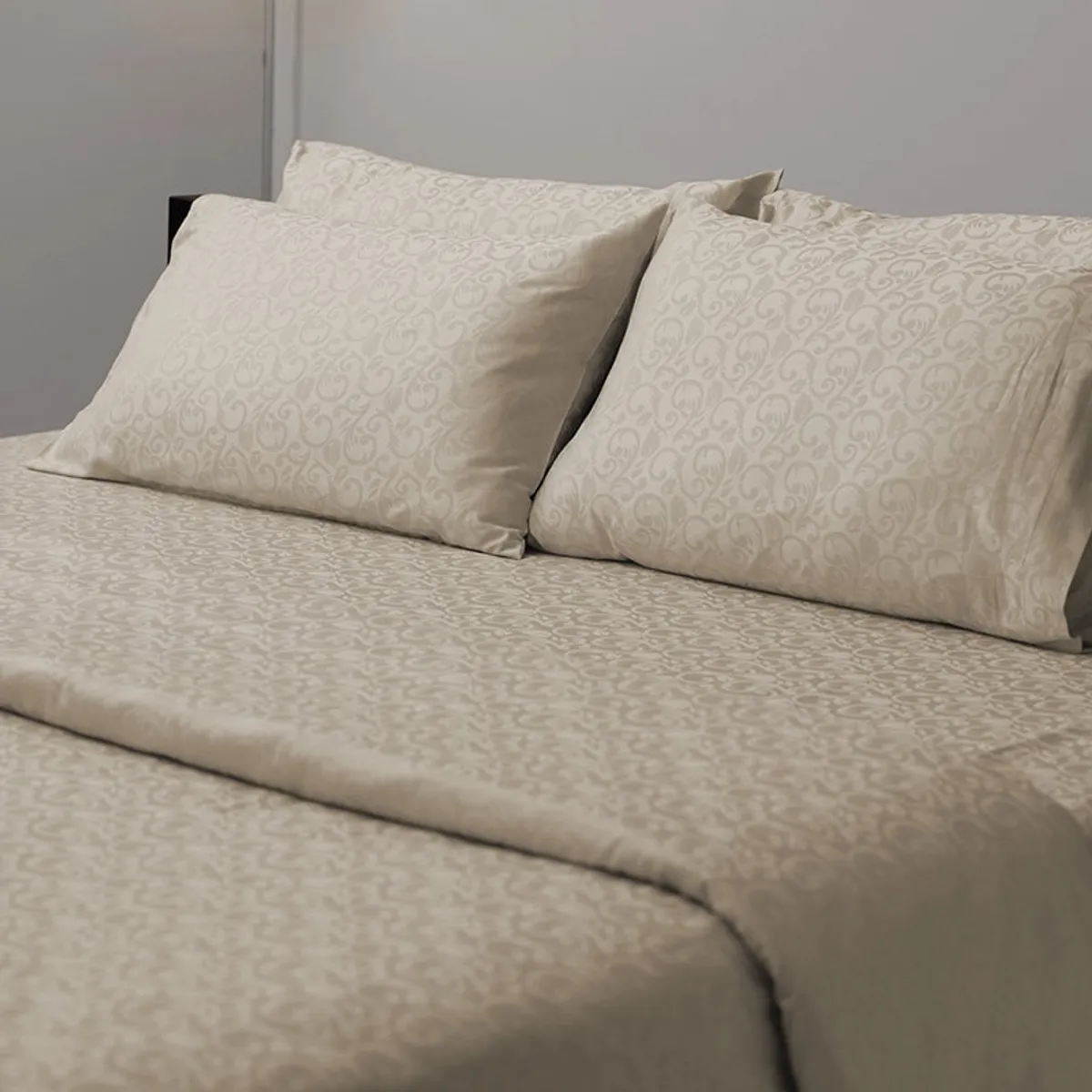 Close view of beige patterned flat bedsheet and matching pillows on a bed
