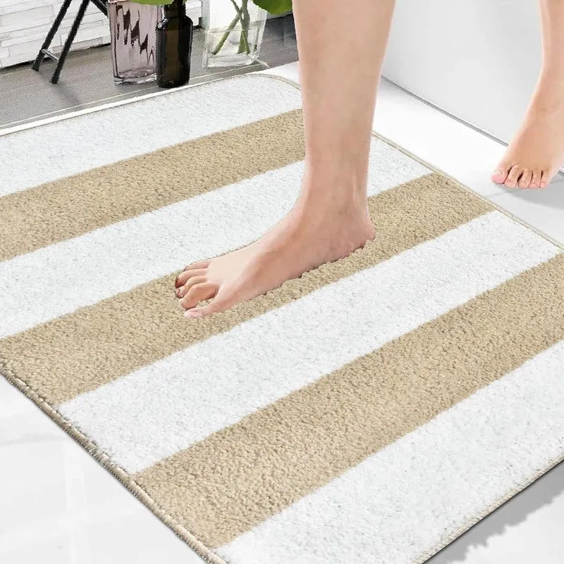 Close-up of a beige and white striped bath mat with a foot resting on it