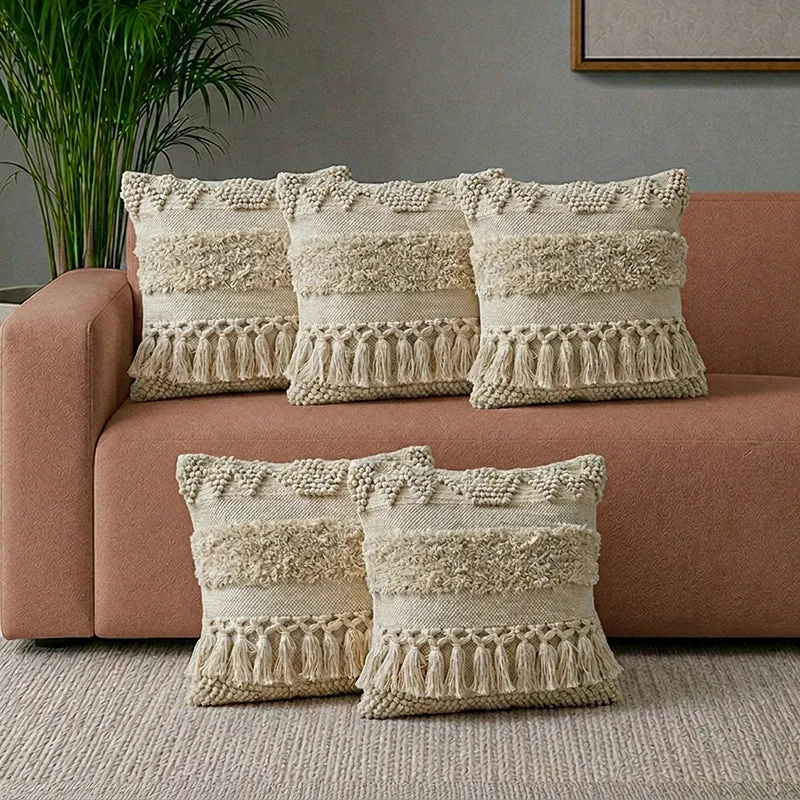 Five grey tufted cushion covers styled on a sofa and floor