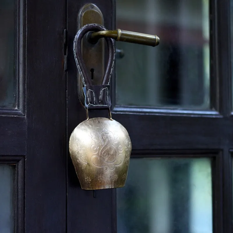 Gold hanging bell displayed on a dark door