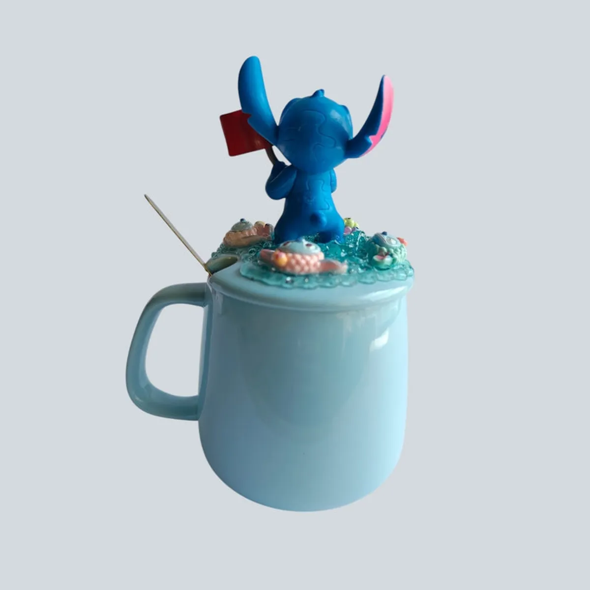 Side view of light blue mug with sculpted Stitch lid and spoon