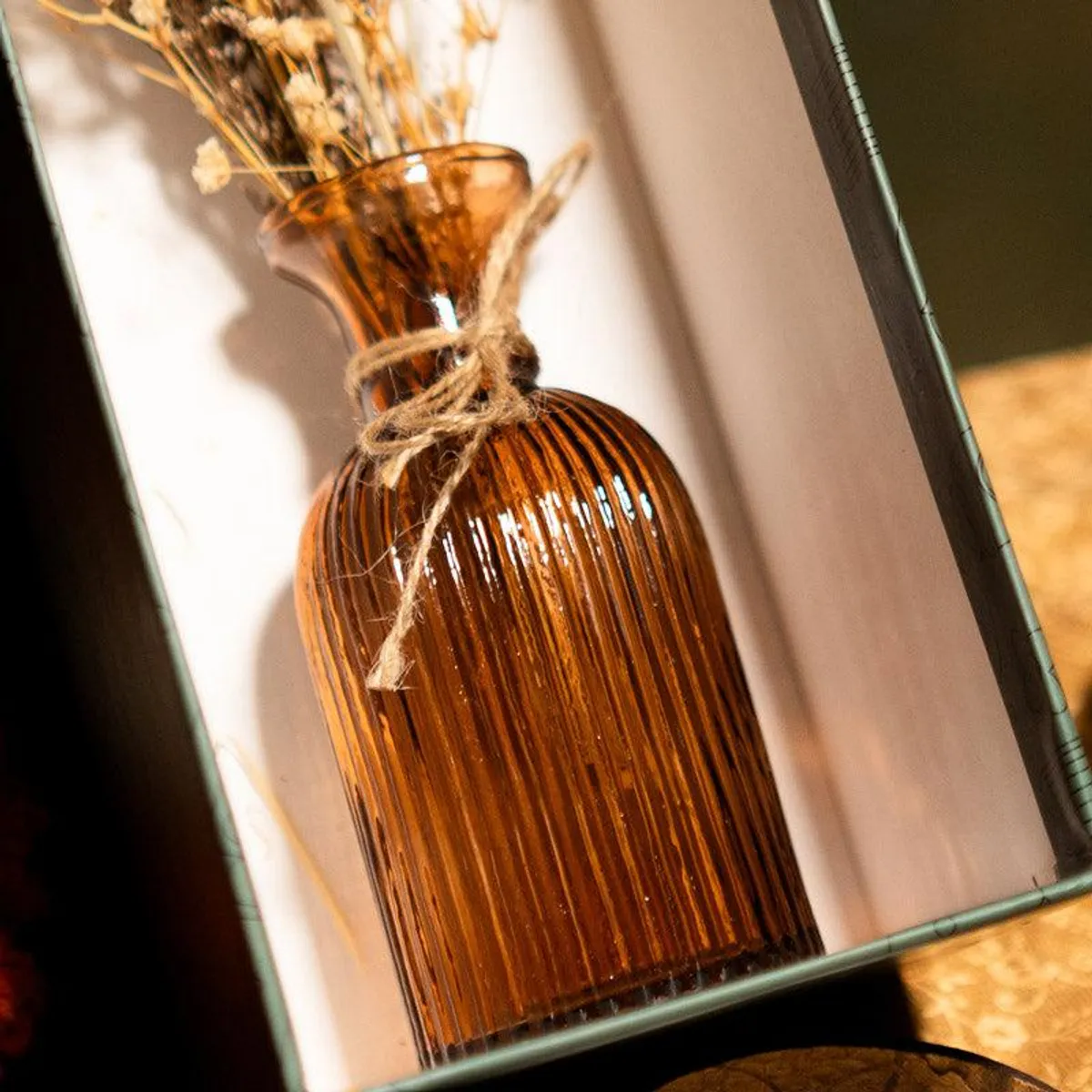 Close-up of the ribbed amber glass vase and dried floral stems
