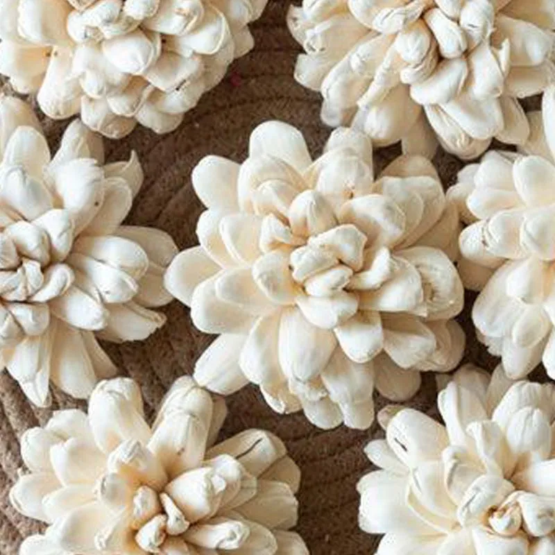 Close-up of layered creamy-white sola wood flowers on a woven mat