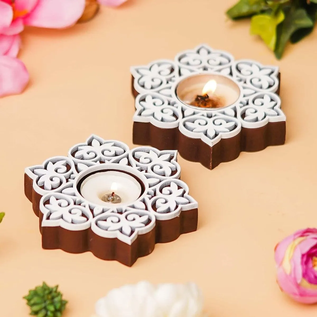 Close view of two brown and white floral tea light holders on a beige surface