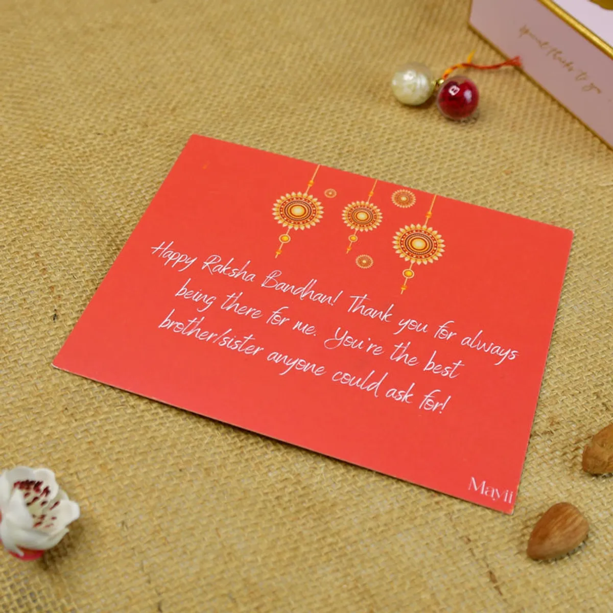 Red Raksha Bandhan greeting card with a festive hanging ornament design.