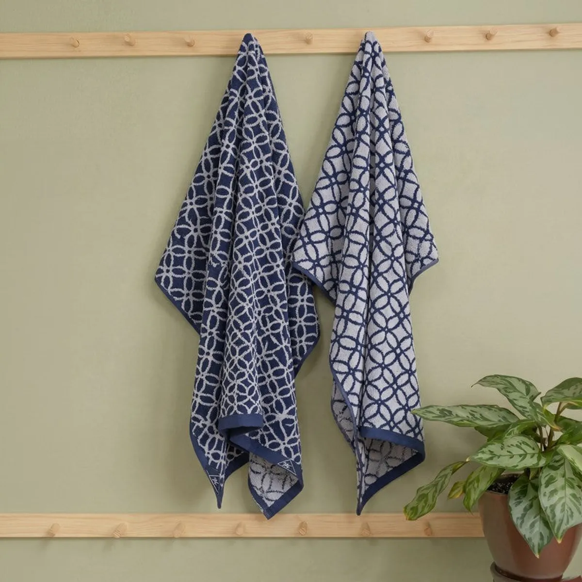 Blue and white patterned bath towels hanging on a wooden wall rack