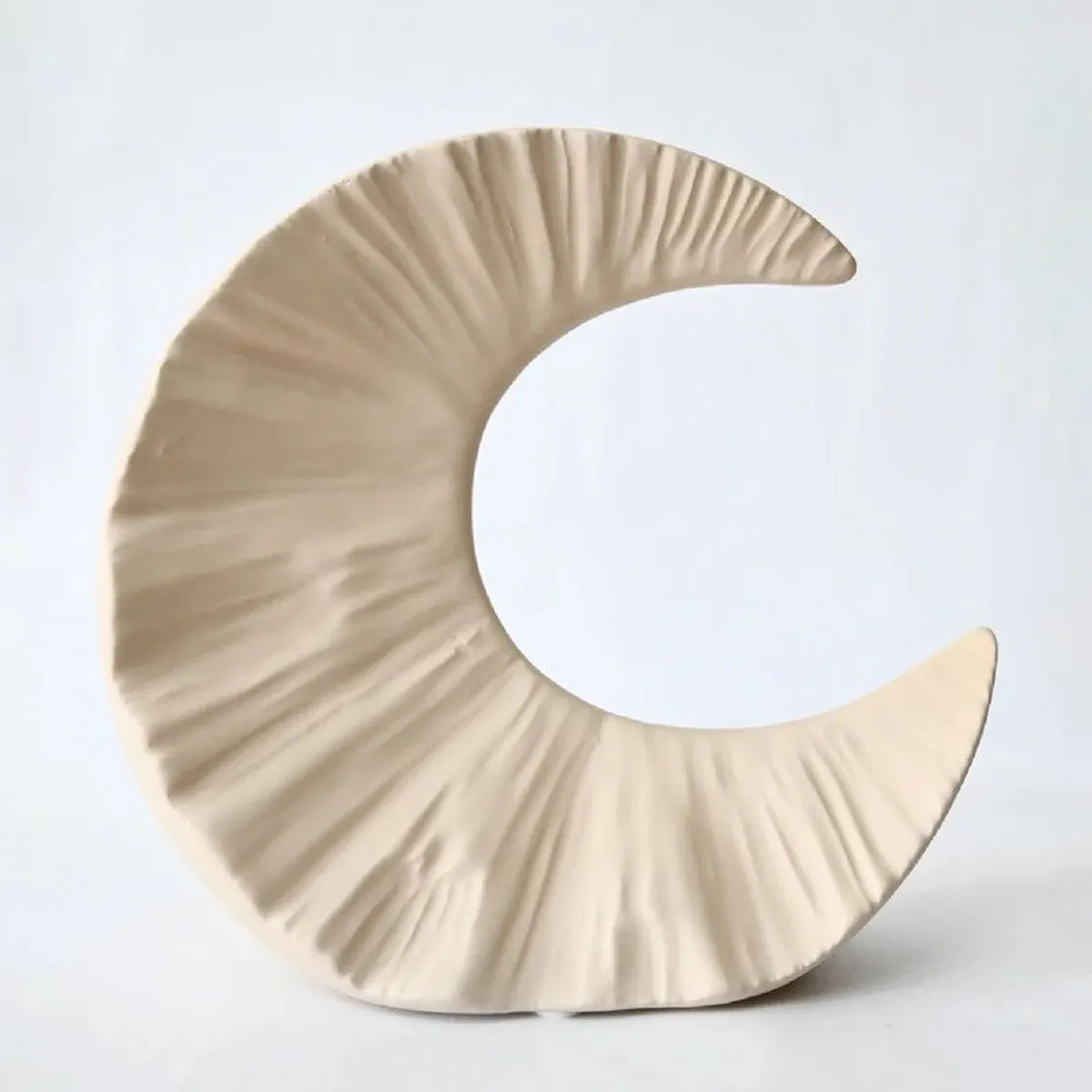 Front view of a beige textured half-moon ceramic vase