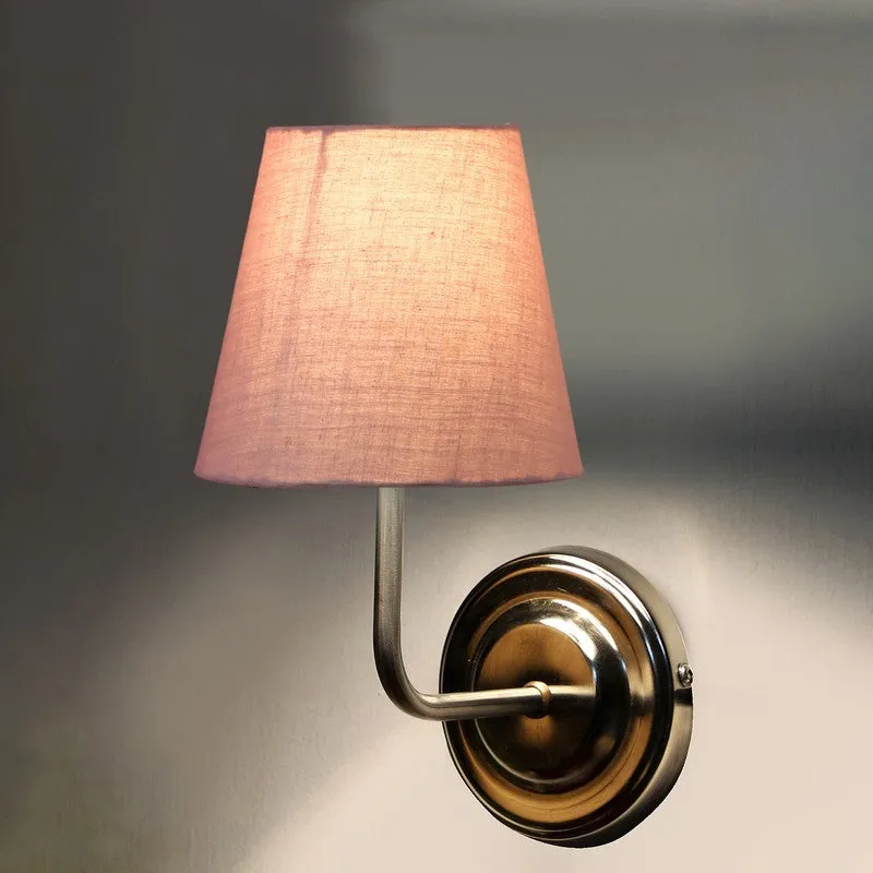 Dusty pink wall lamp glowing against a dark wall