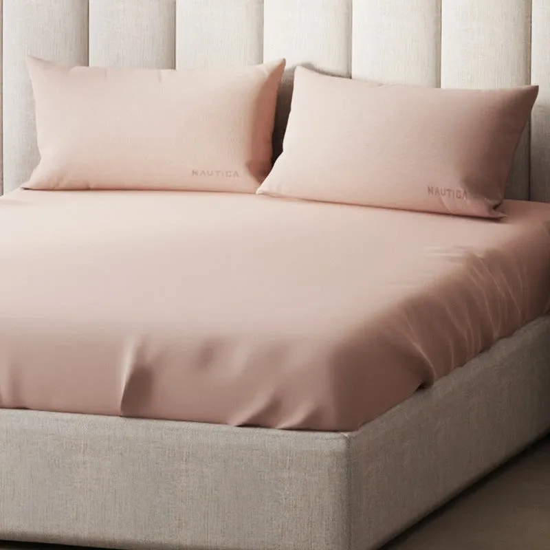 Close-up of a smooth pink bedsheet and matching pillow covers on a bed