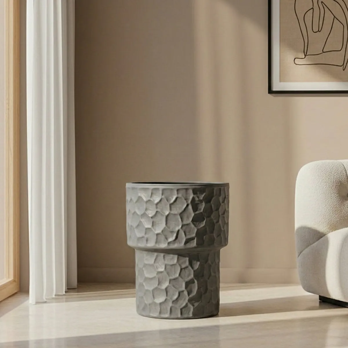 Grey textured pedestal planter beside a neutral armchair
