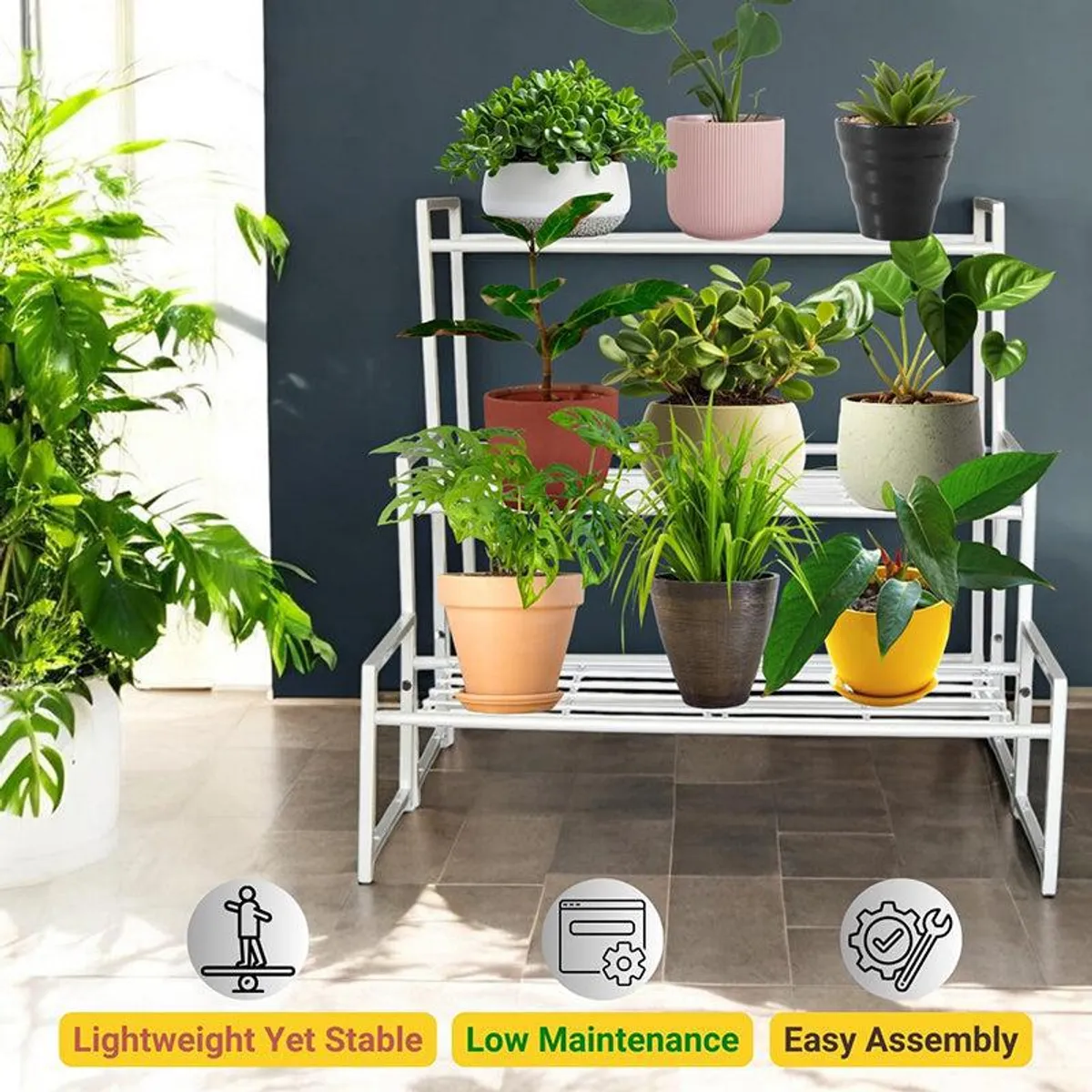 White three-tier metal plant stand filled with colourful potted plants