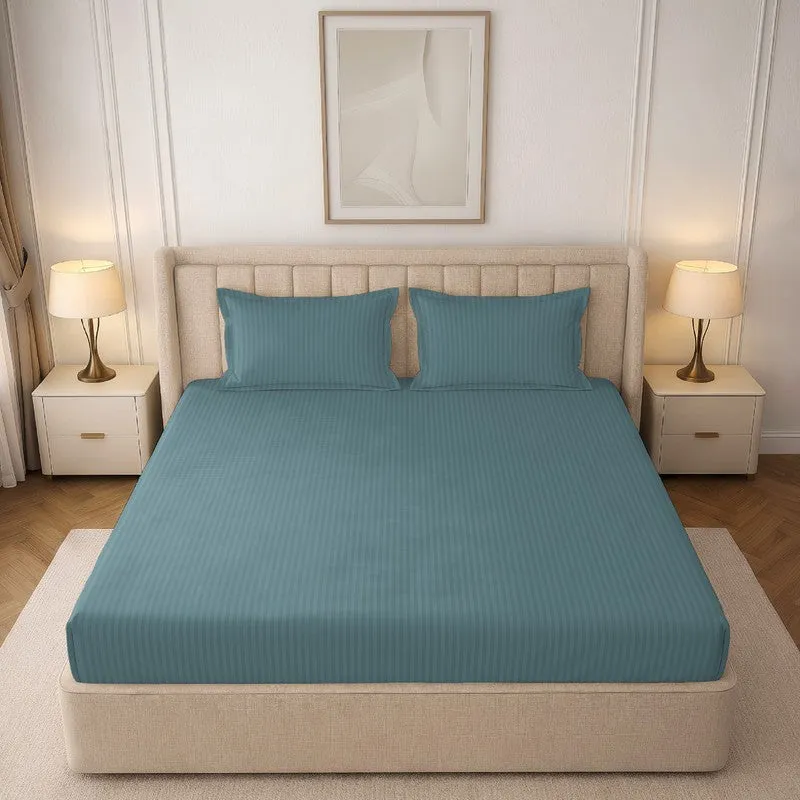 Teal striped fitted bedsheet styled on a double bed with two matching pillow covers