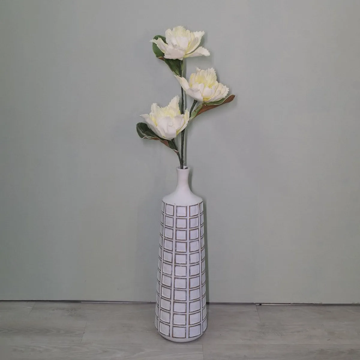 White three-flower artificial dahlia stem against a plain wall