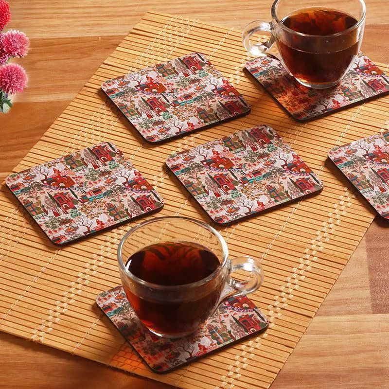 Printed square coasters arranged on a bamboo mat with two glass teacups