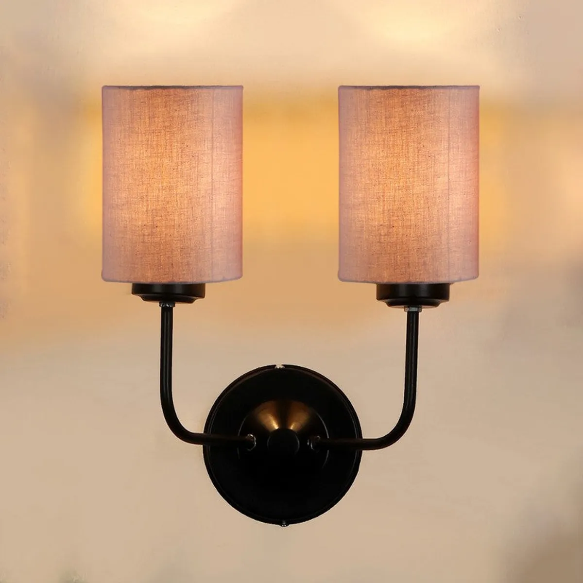Front view of lit muted beige wall lamp on wall