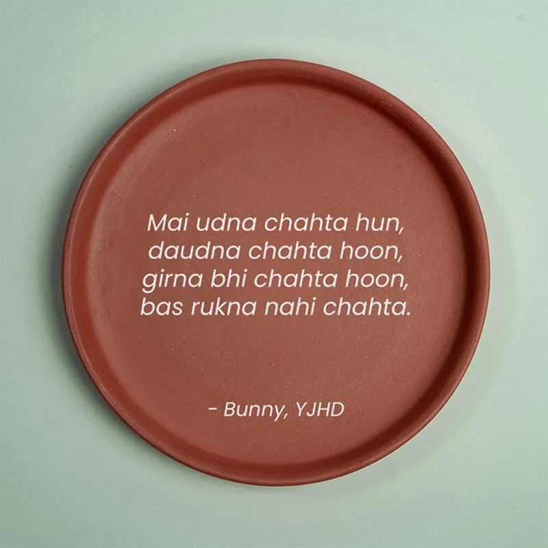 Front view of round terracotta wall plate with white quote on pale green background