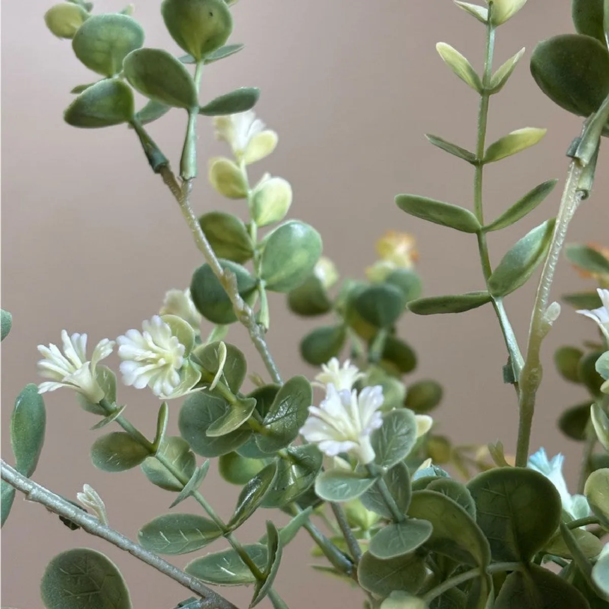 Detailed view of pale artificial flowers and green eucalyptus foliage