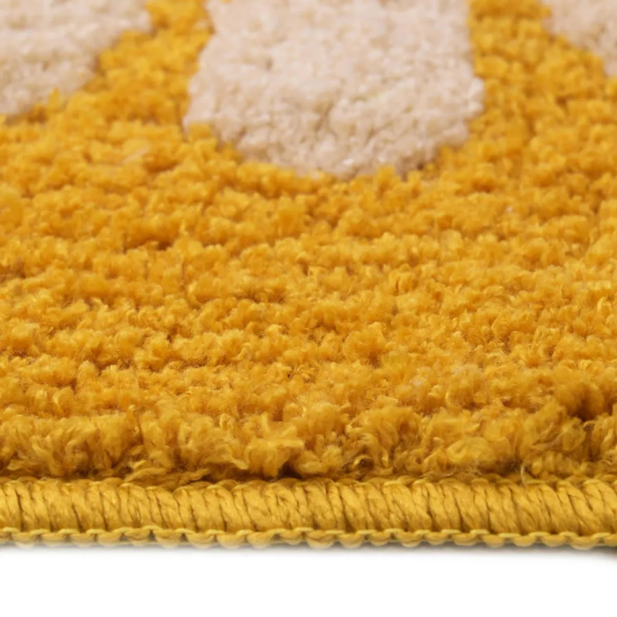 Close-up view of the yellow bathmat's soft textured surface and cream floral motif