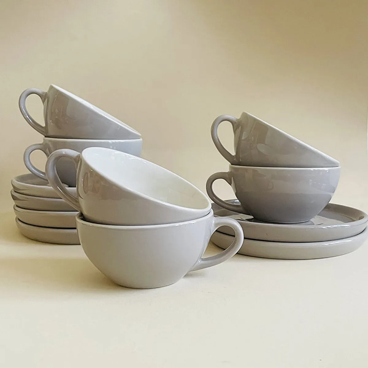 Six grey cups and saucers arranged in a layered tabletop display