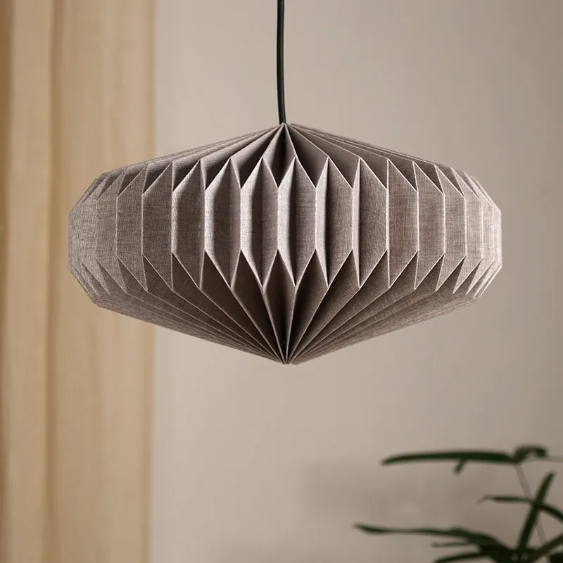 Unlit grey pleated paper ceiling lamp hanging against a warm neutral backdrop