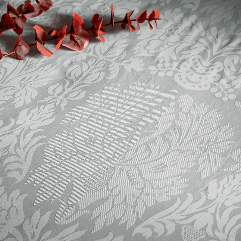 Close-up of the light grey floral jacquard-style bedding pattern