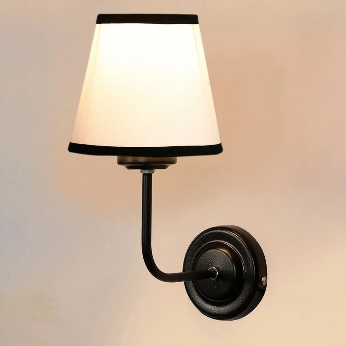 Front angled view of white shade wall lamp with black iron arm