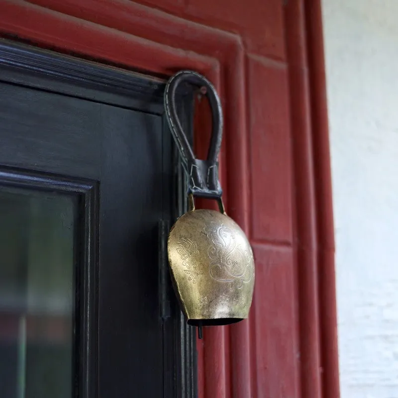 Side view of a gold hanging bell against a red and black doorway