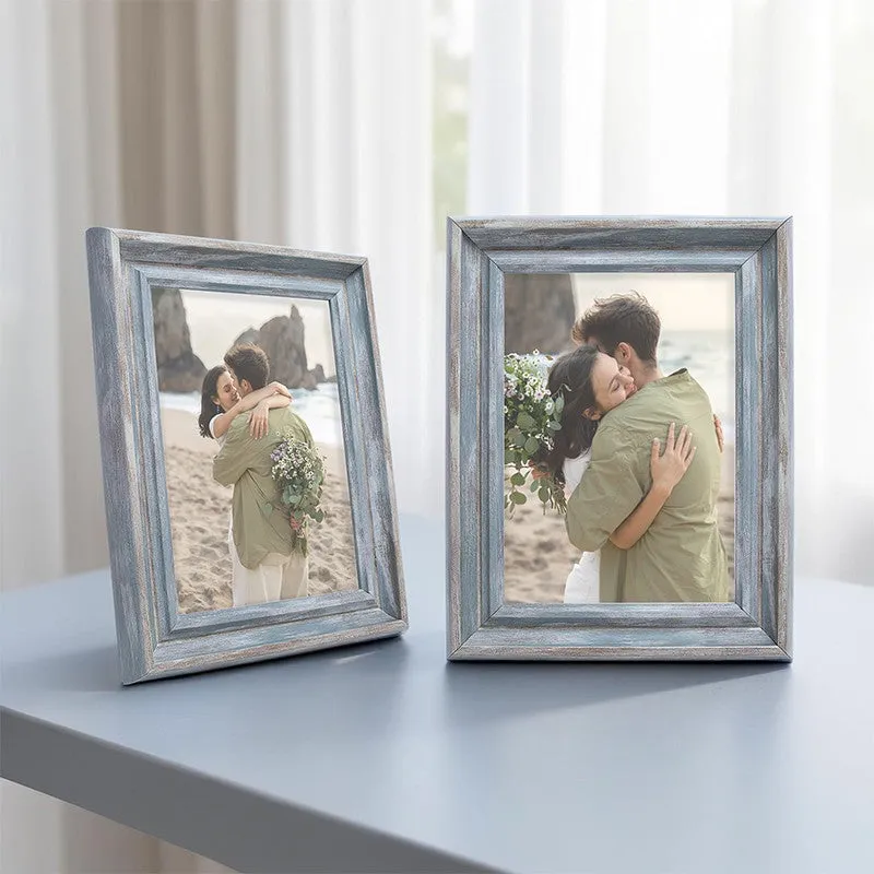 Two blue-grey rectangular photo frames displayed on a blue tabletop