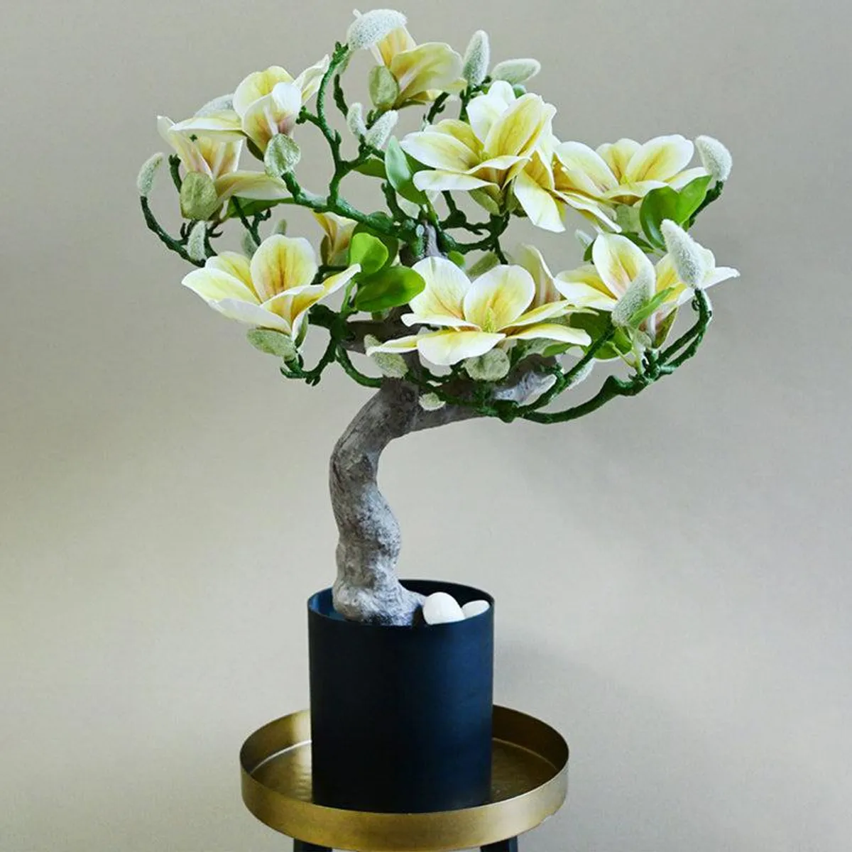 White and yellow artificial magnolia tree with a curved trunk in a black pot