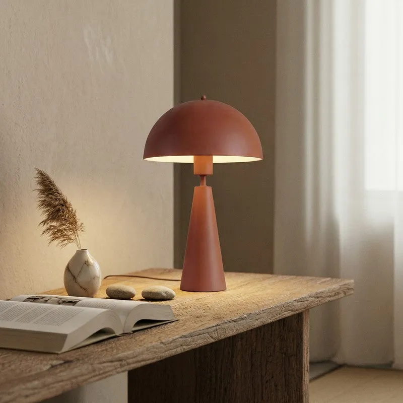 Brown table lamp styled on a wooden table beside a vase and open book